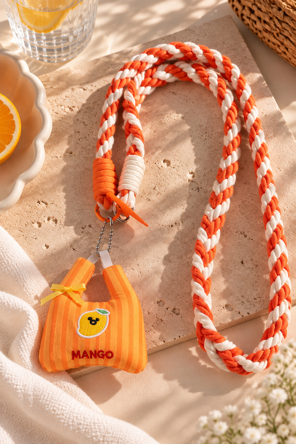 Bijou de téléphone Léonie tressé orange et blanc, avec attache sur une coque de téléphone